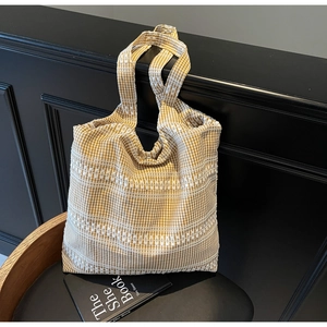 Detailed view of yellow plaid canvas tote bag with white lace trim on a wooden chair