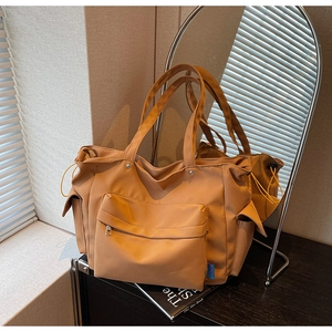 Detail view of khaki nylon tote bag featuring front zipper pocket and side drawstring