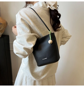 Detail of black lychee leather bucket bag with wooden bead charm and shoulder strap