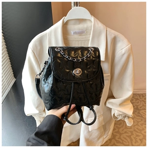 Detail of black quilted star pattern backpack with silver twist lock and chain handle