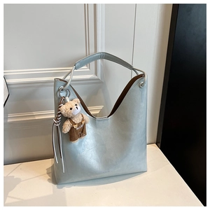 Close-up of light blue PU leather tote bag with cute teddy bear plush pendant detail