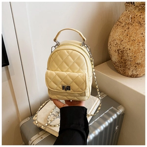 Detail of cream quilted mini backpack featuring metal turn-lock and chain strap