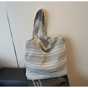 Detail of black and white gingham tote bag with horizontal white embroidery lines