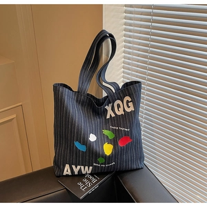 Detail of striped denim tote bag with colorful abstract paint art and XQG lettering