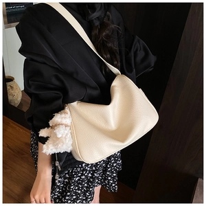 Beige Hobo-Tasche mit Litschimuster und süßem Bärenanhänger an der Schulter des Models