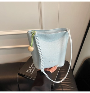 Macro shot of light blue lychee pattern leather bucket bag with wooden bead charm detail