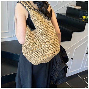 Detail of hand-woven straw shoulder bag with hollow lace pattern and black trim