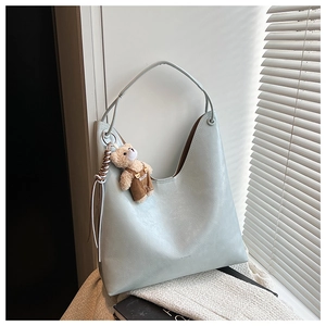 Detail of light mint green hobo bag with pebble texture and cute bear pendant charm