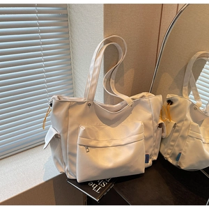 Close-up of a white nylon tote bag with orange drawstring side pockets and large capacity