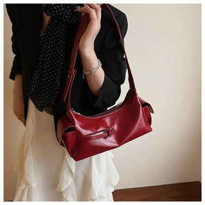 Detail of dark red oil-wax leather hobo bag featuring side flap pockets and zip accents