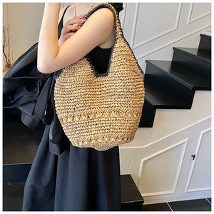 Detailed texture of straw woven tote bag with black trim accents in minimalist indoor setting
