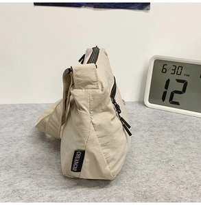 Vue détaillée du sac à bandoulière en nylon beige avec une étiquette textile de marque