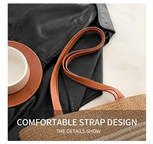 Detail of brown faux leather shoulder straps with white stitching on a straw tote bag