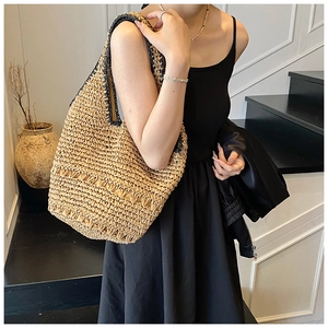 Detail of handmade straw hobo bag showing intricate woven textures and dark trim accents
