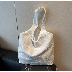 Detailed view of white canvas tote bag with textured embroidery on leather seating
