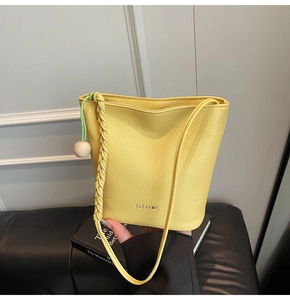 Detail of yellow lychee-grain bucket bag featuring a wooden bead and woven handle
