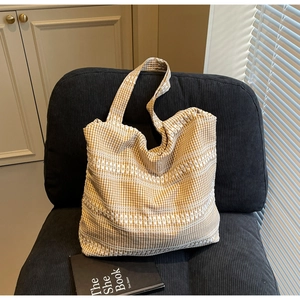 Detailed view of yellow gingham tote bag with textured embroidery on a cozy chair