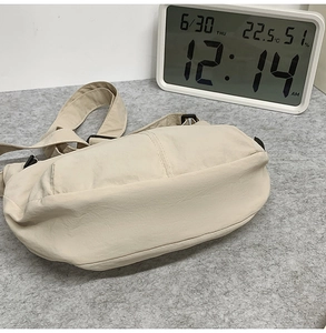 Vue de dessus du sac croissant crème en nylon texturé avec bandoulière textile réglable