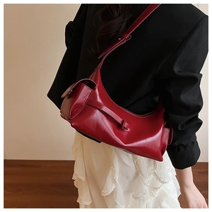 Side view of a glossy red shoulder bag with side pocket shown on a model