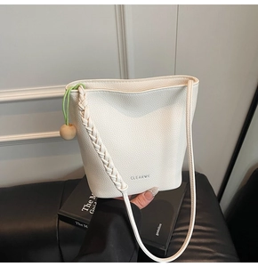 Detail of white lychee leather bucket bag featuring woven handle and green drawstring