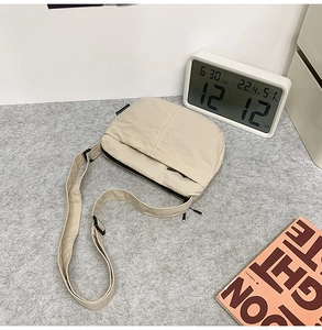 Détail du sac bandoulière en nylon beige avec double compartiment zippé et sangle réglable