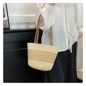 Detail of a large straw tote bag with brown stripes and durable faux leather shoulder straps