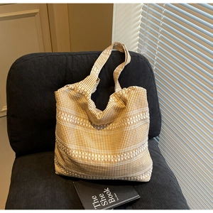 Close-up of yellow and white checkered canvas tote bag with horizontal embroidery on a chair