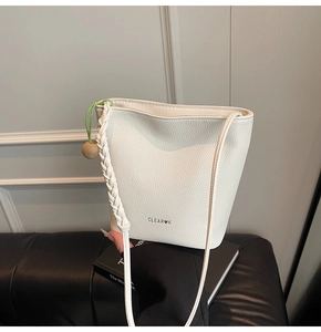 Detail of white bucket bag with lychee texture, clear logo, and woven strap design