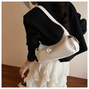 Détail du sac hobo crème en similicuir mat porté à l'épaule par un mannequin féminin