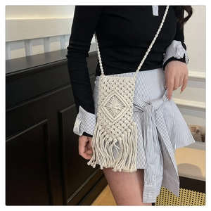 Gros plan sur un sac de téléphone blanc tissé à la main avec pompons et textures
