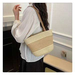 Detail view of straw tote bag with brown stripes and durable leather shoulder straps