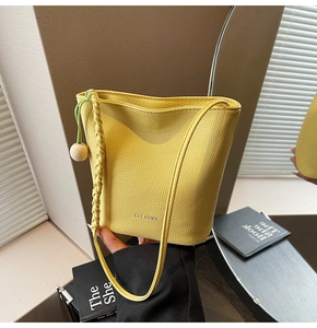 Detail of yellow lychee pattern bucket bag with CLEAROK logo and wood bead charm