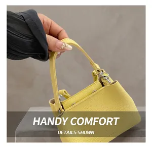 Détail d'un sac à main jaune en cuir grainé avec boucle argentée et poignée souple