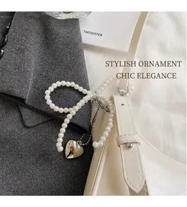 Dettaglio borsa in pelle PU bianco sporco con catena di perle e ciondolo a cuore su blazer