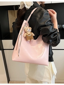 Pink PU leather tote bag with a cute teddy bear charm worn by a model in a casual setting