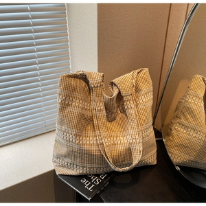 Detail view of yellow and white checkered tote bag with white geometric embroidery on books
