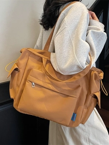 Large khaki tote bag with front pocket and drawstring side pouches for daily commute