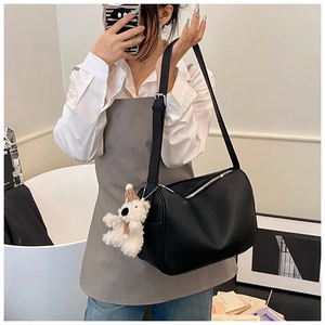 Detail einer schwarzen Leder-Zylindertasche mit weißem Plüschbär-Anhänger und Reißverschluss