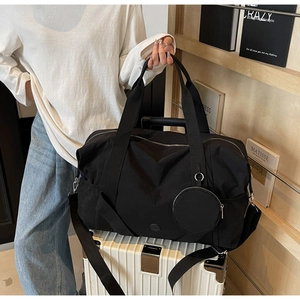 Detail einer großen schwarzen Reisetasche mit Gurt und kleiner runder Zusatztasche