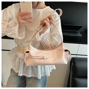 Detail of pink glossy leather hobo bag featuring side buckle and adjustable shoulder strap