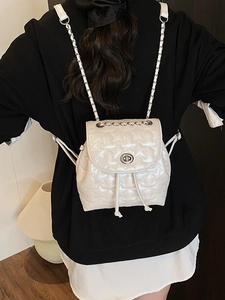 White quilted star pattern backpack with silver chain strap and twist lock on a model