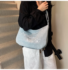 Détail du sac cabas en denim bleu clair avec lettres vintage et motifs de lion d'art
