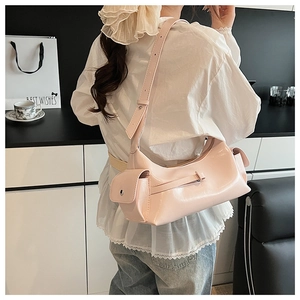 Détail d'un sac sous le bras rose en forme de croissant avec poche latérale et sangle