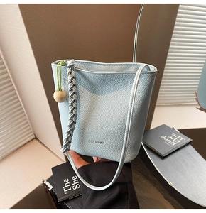Detail of light blue lychee pattern bucket bag with woven strap and wood bead accessory