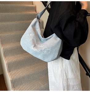 Détail du sac hobo en toile bleu clair avec broderie lion et texte Sunshine Nika élégant