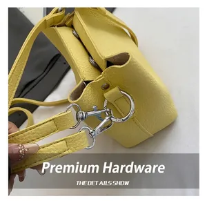 Gros plan du crochet en métal argenté et de la texture cuir du sac seau jaune