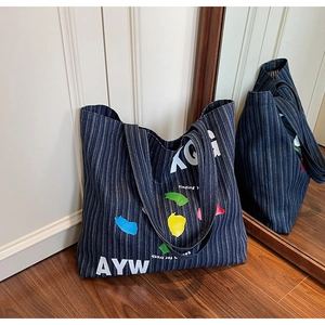 Detail of navy blue striped denim tote bag with colorful abstract art and letters