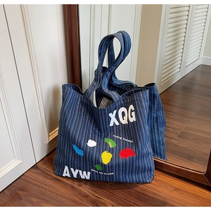 Detail of striped denim tote bag with artistic lettering and colorful graphic print
