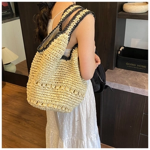 Detail view of handmade woven straw shoulder bag with black contrast trim and straps