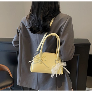 Borsa a conchiglia gialla con fiocco e ciondolo di perle mostrata su modella